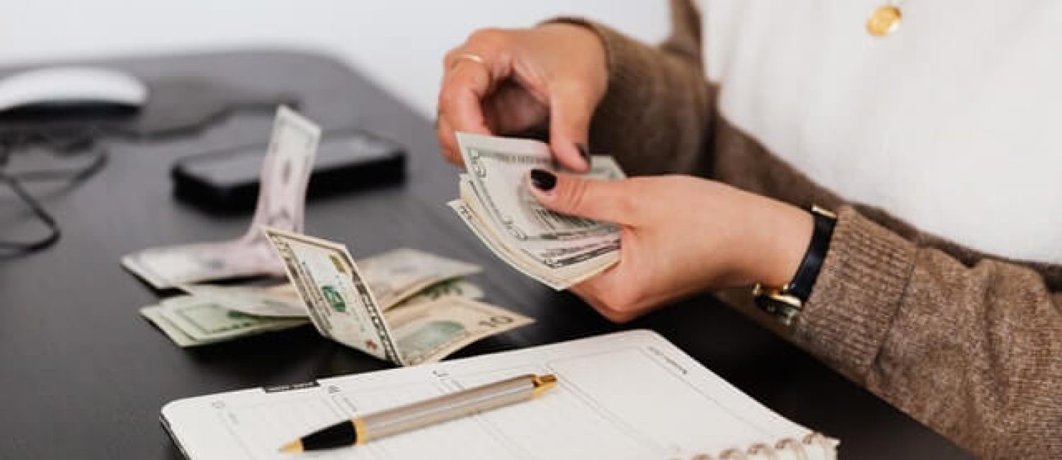 crop payroll clerk counting money while sitting at table